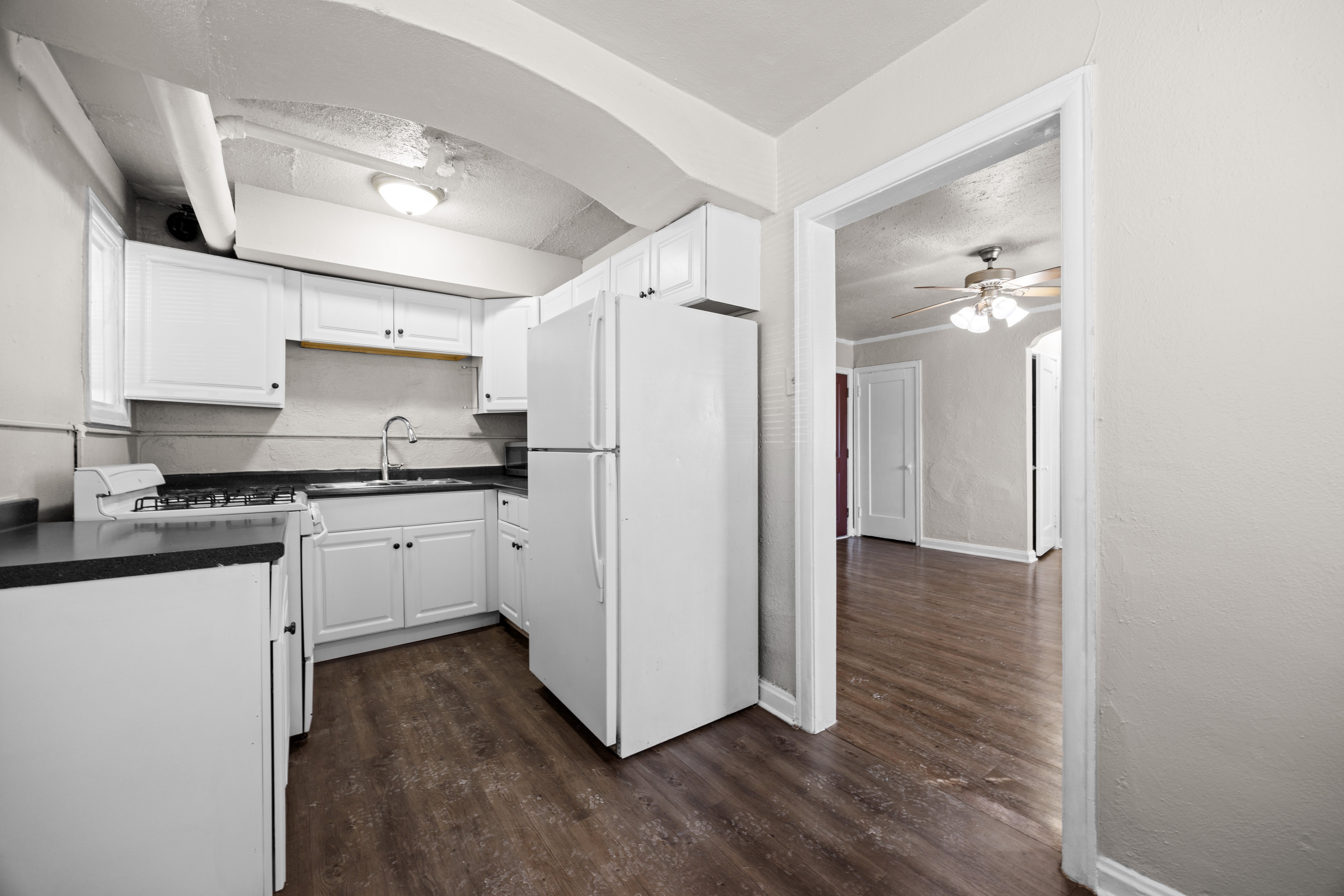A kitchen with white cabinets and a black counter top.